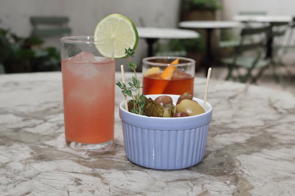 Colorful cocktails and a savory snack on a marble table at a New York cafe.
